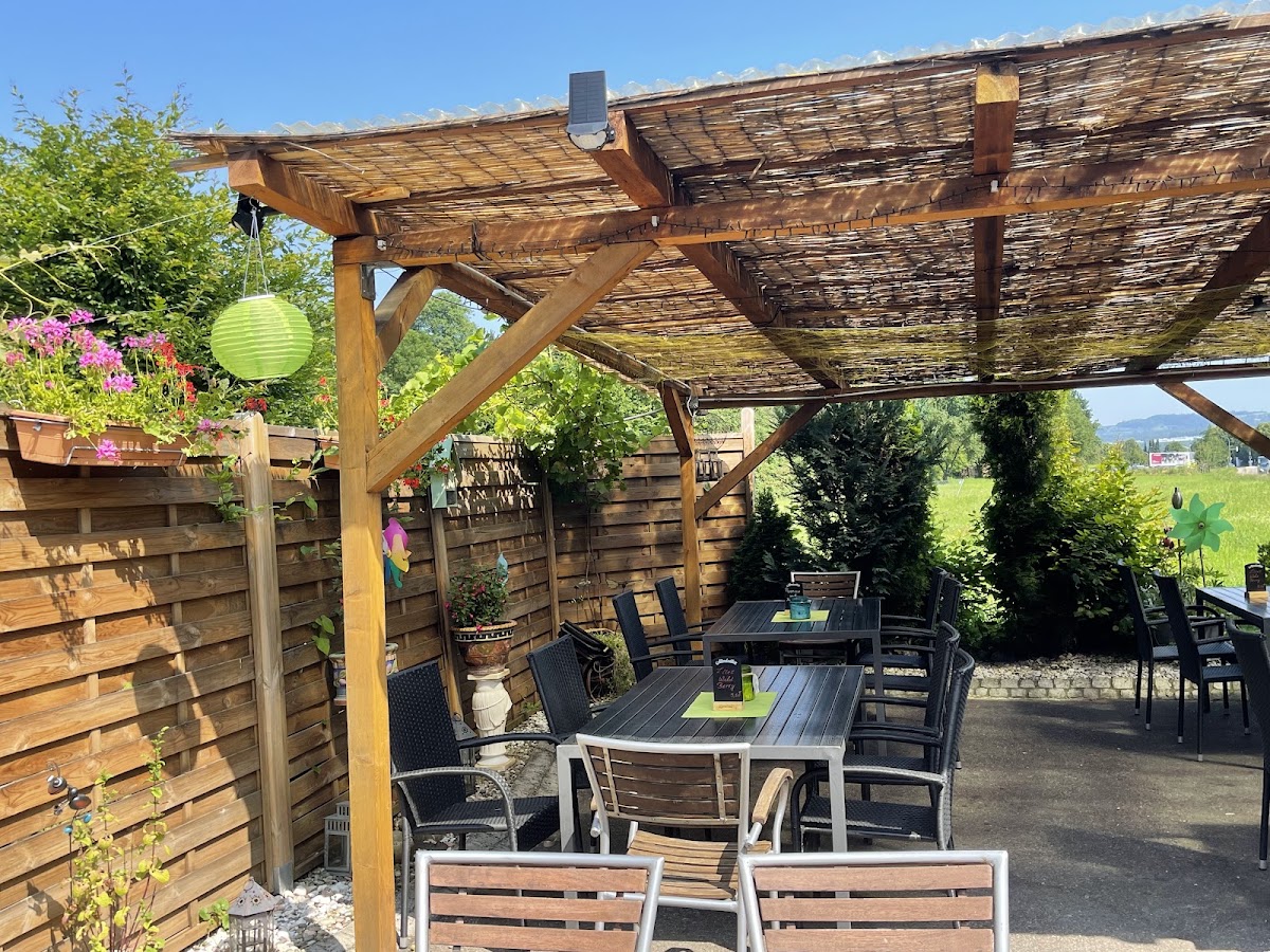 Gemütliche überdachte Terrasse der Gaststätte Frühlingsau mit Sitzgruppen im Freien